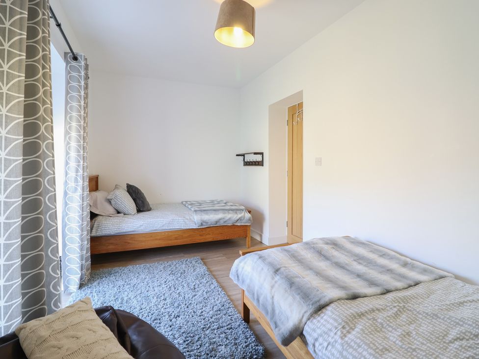 A bedroom with two beds and a rug at Tyn Y Weirglodd in Deiniolen