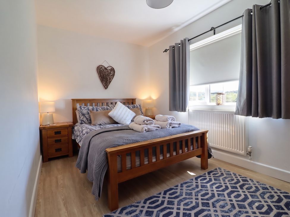 A bedroom with a bed and nightstand at Tyn Y Weirglodd in Deiniolen