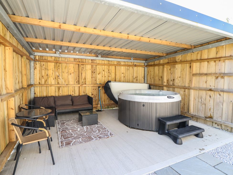 An outdoor space with a hot tub and seating area at Tyn Y Weirglodd in Deiniolen