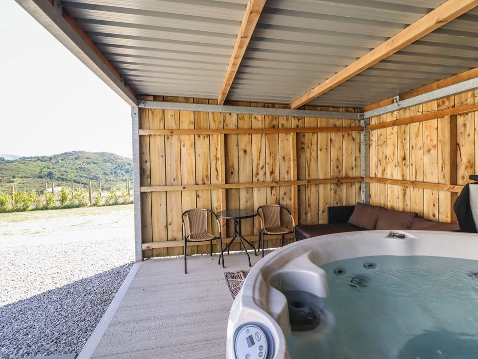 An outdoor area with a hot tub and seating at Tyn Y Weirglodd in Deiniolen