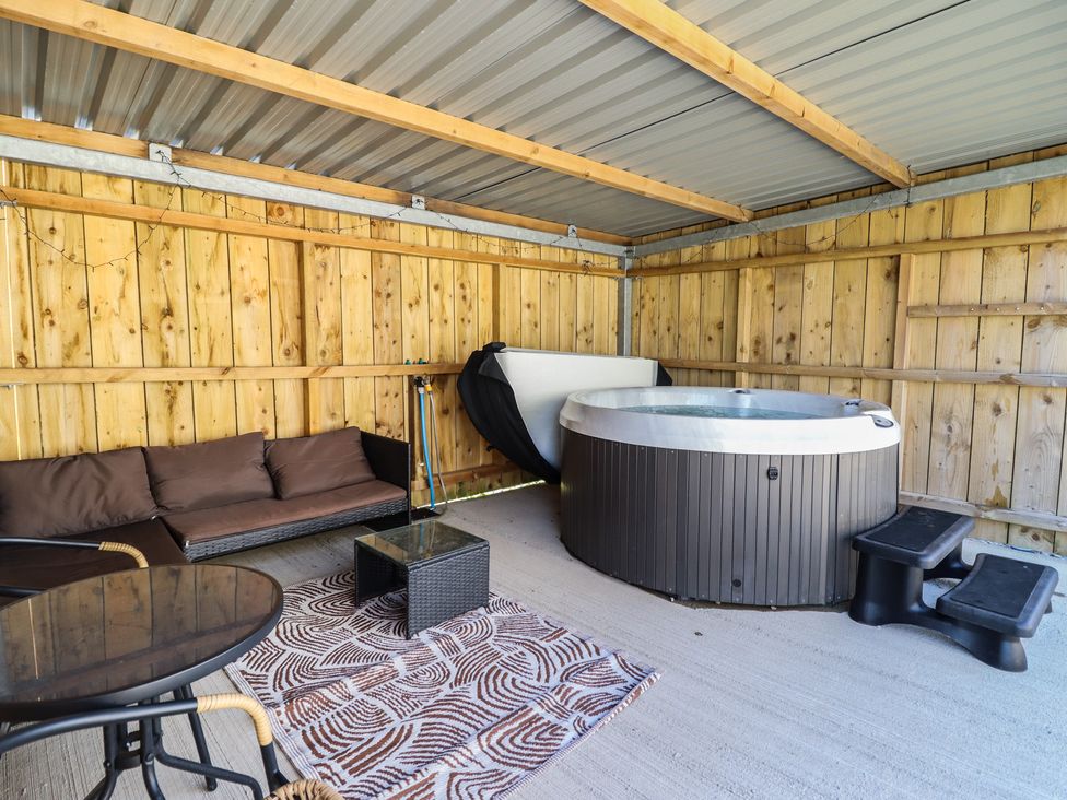 An outdoor area with a hot tub and seating at Tyn Y Weirglodd in Deiniolen