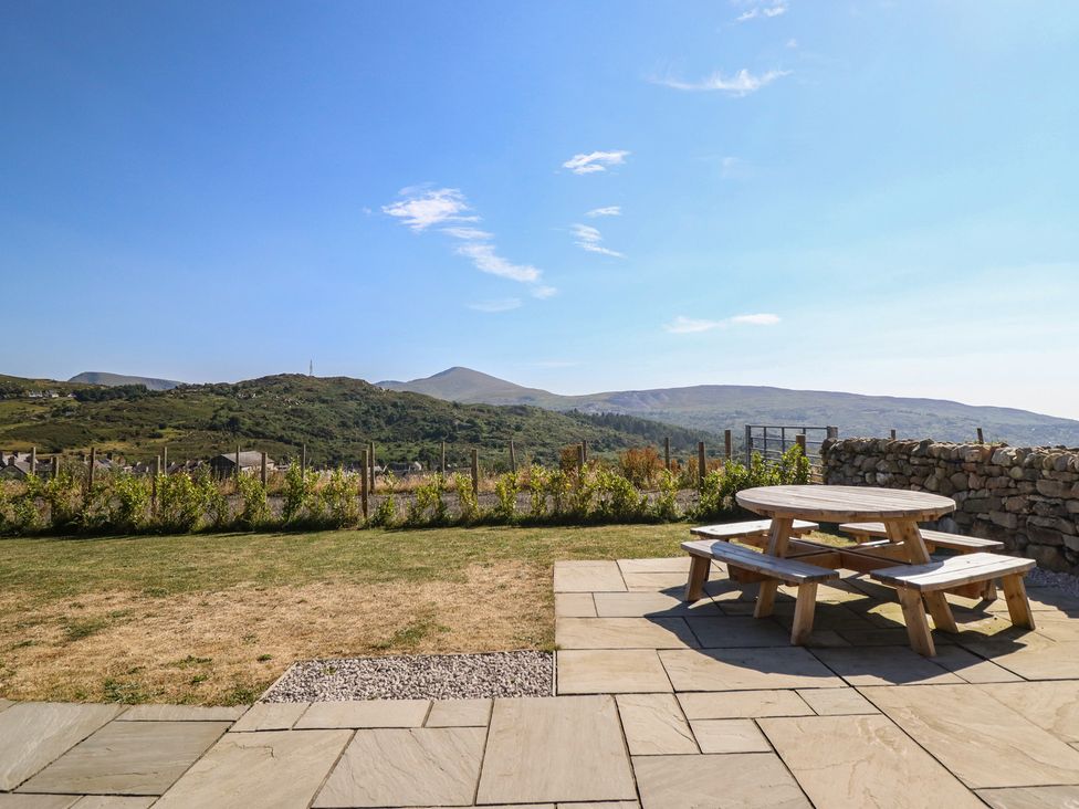 A garden with a picnic table and benches at Tyn Y Weirglodd in Deiniolen