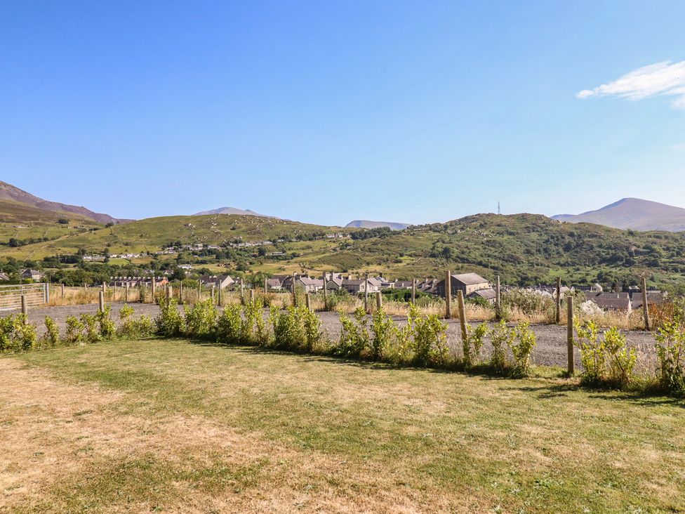 A view of houses and mountains with a grassy area at Tyn Y Weirglodd in Deiniolen
