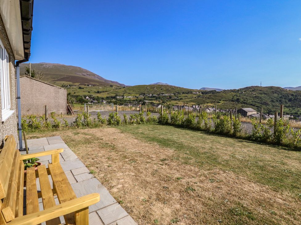 A garden with a bench and grass lawn at Tyn Y Weirglodd in Deiniolen
