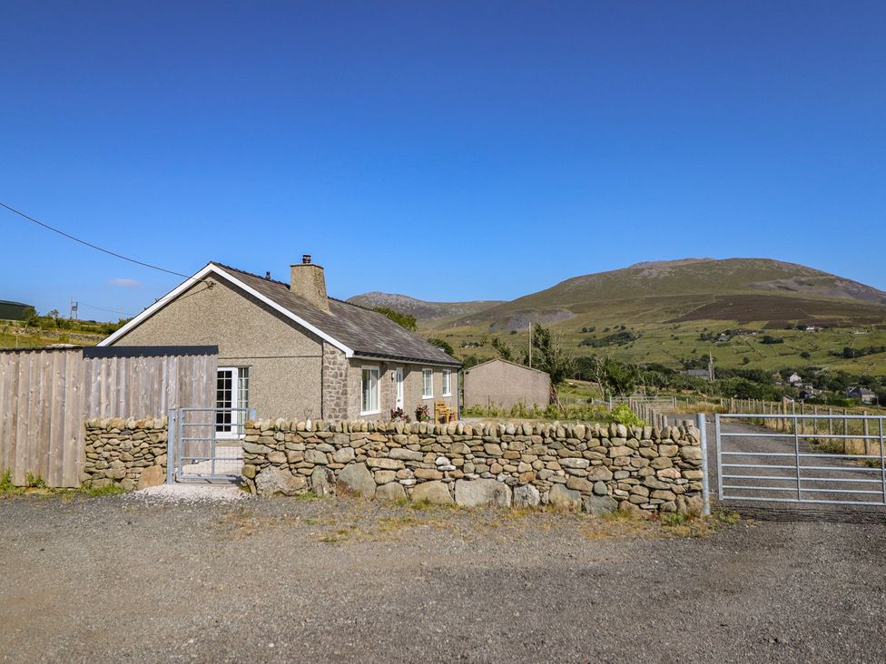 A house with a stone wall and a gate at Tyn Y Weirglodd in Deiniolen