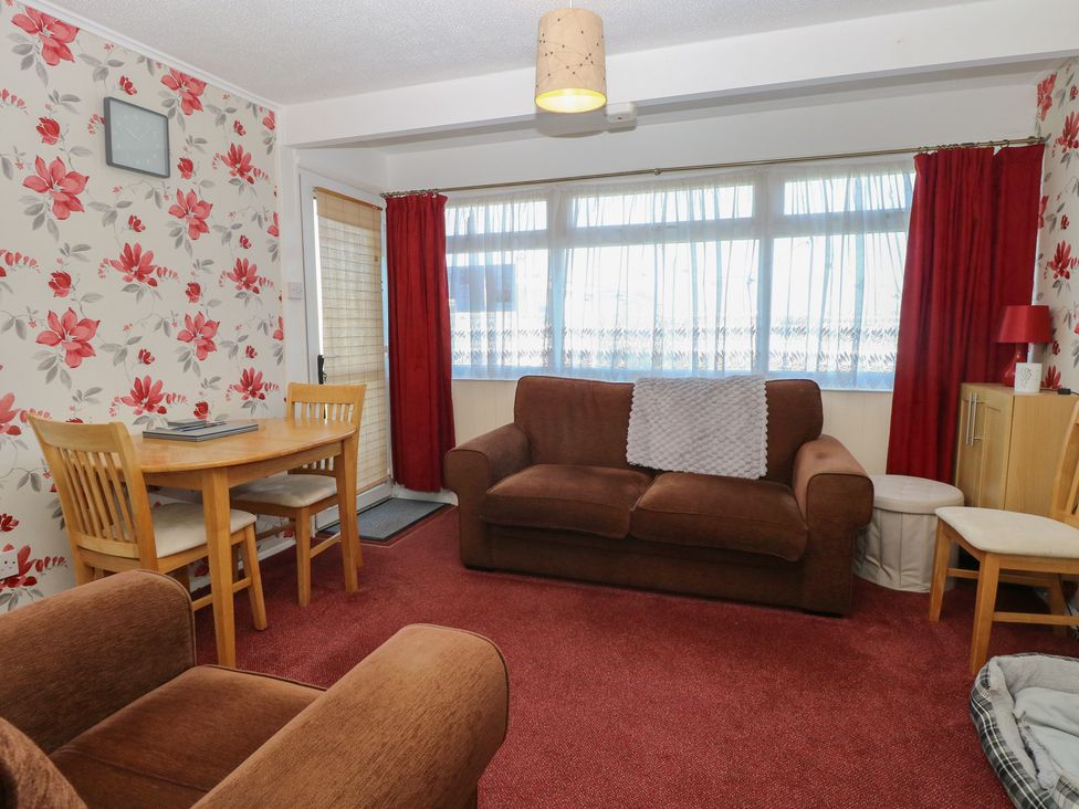 A living room with a sofa and dining table at Mon Chalet in Hemsby