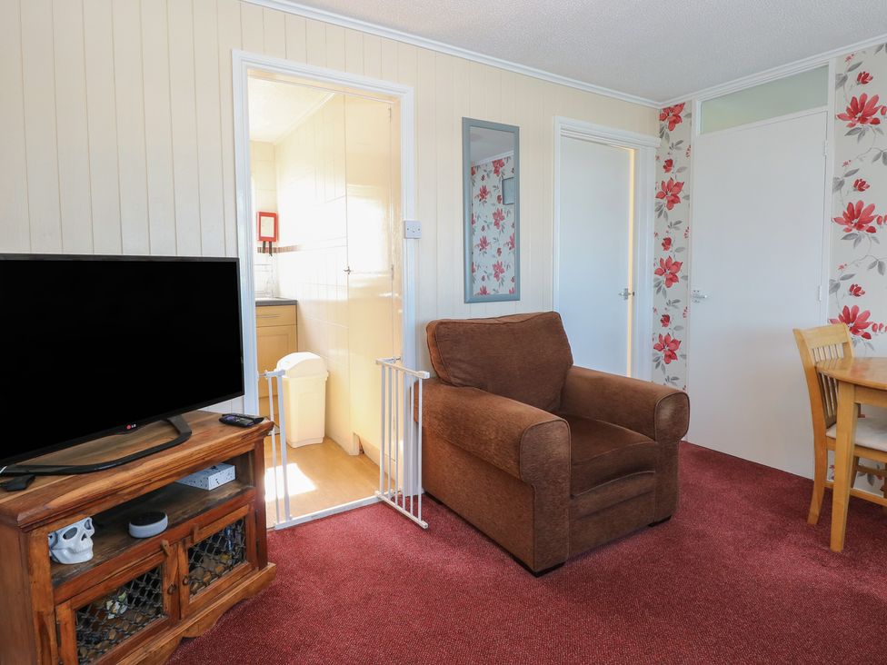 A living room with a television and armchair at Mon Chalet in Hemsby