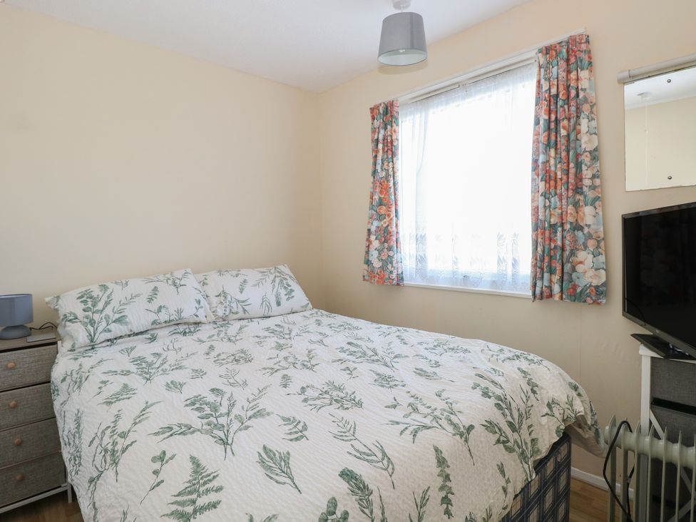 A bedroom with a bed and television at Mon Chalet in Hemsby