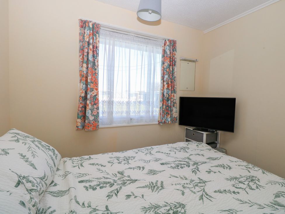 A bedroom with a bed and television at Mon Chalet in Hemsby