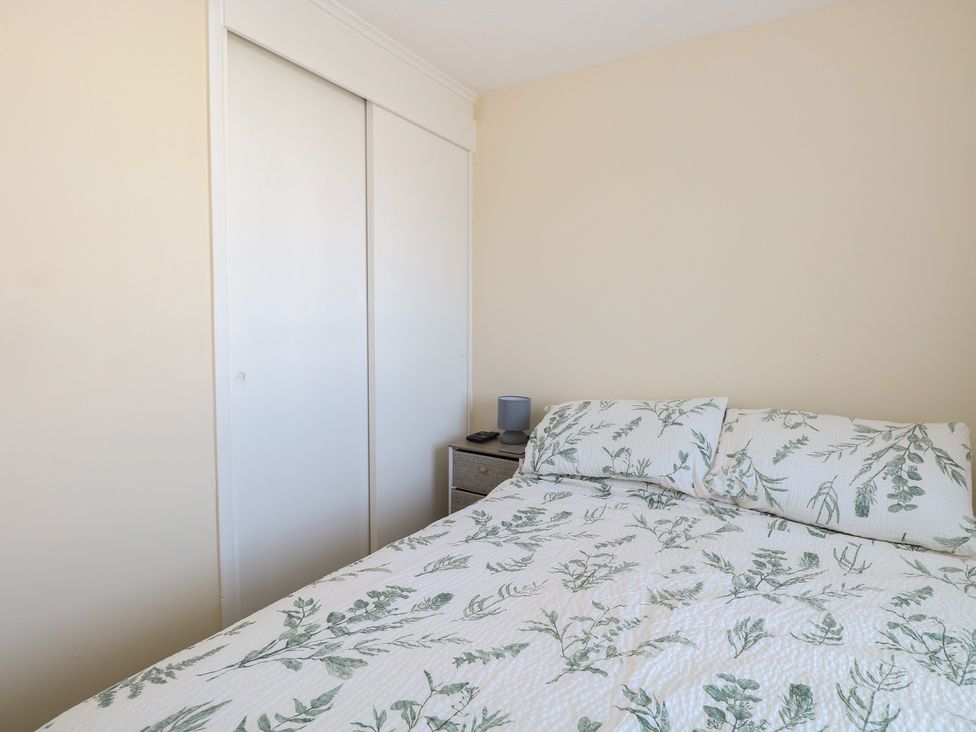 A bedroom with a bed and bedside table at Mon Chalet in Hemsby