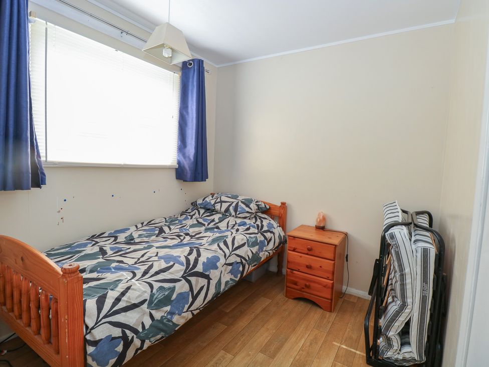 A bedroom with a bed and nightstand at Mon Chalet in Hemsby