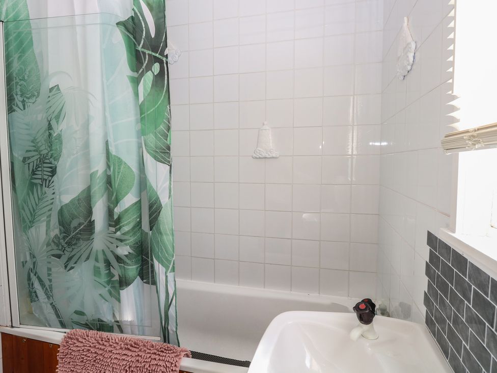 A bathroom with a shower, bathtub, and towel at Mon Chalet in Hemsby