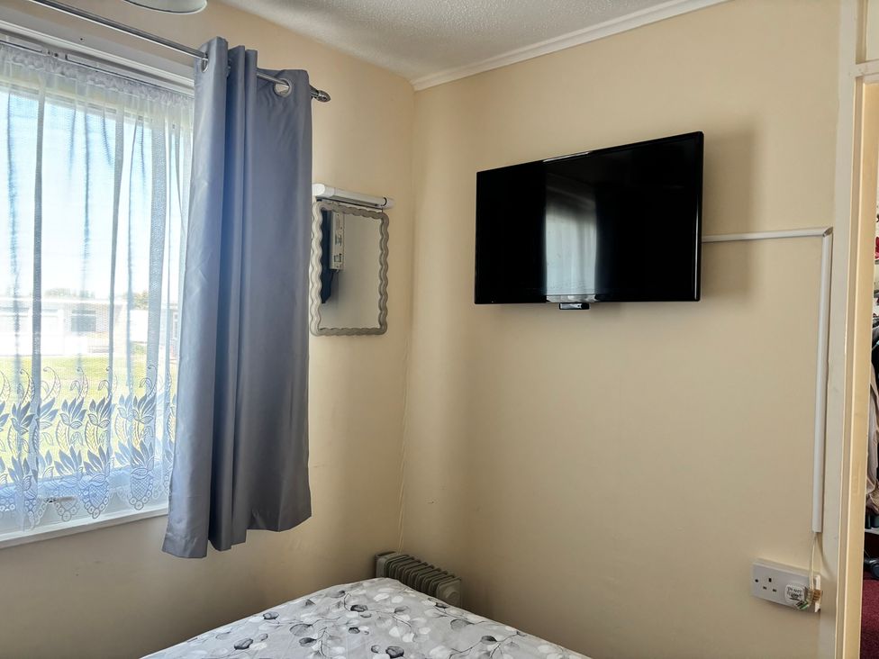 A bedroom with a television and a mirror at Mon Chalet in Hemsby