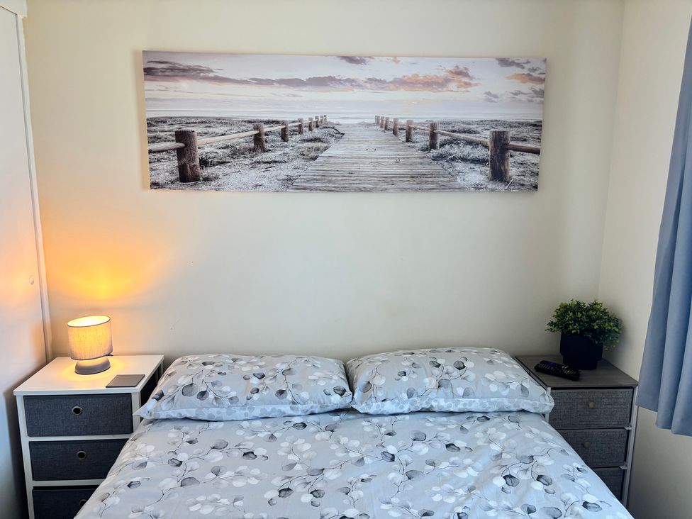 A bedroom with a bed and bedside table at Mon Chalet in Hemsby
