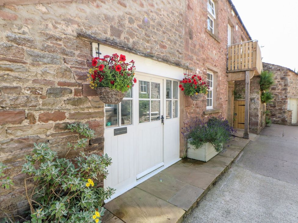 An outdoor view of the entrance door with flower baskets at Dairy Cottage Kirkby Stephen