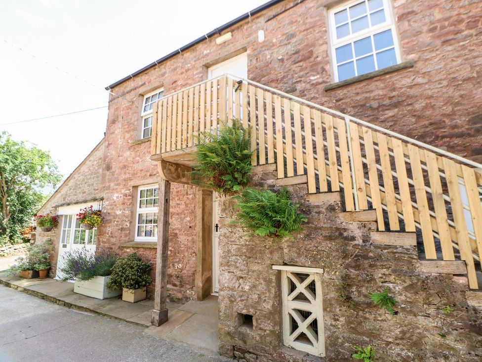 A stone building with stairs and planters at Dairy Cottage in Kirkby Stephen