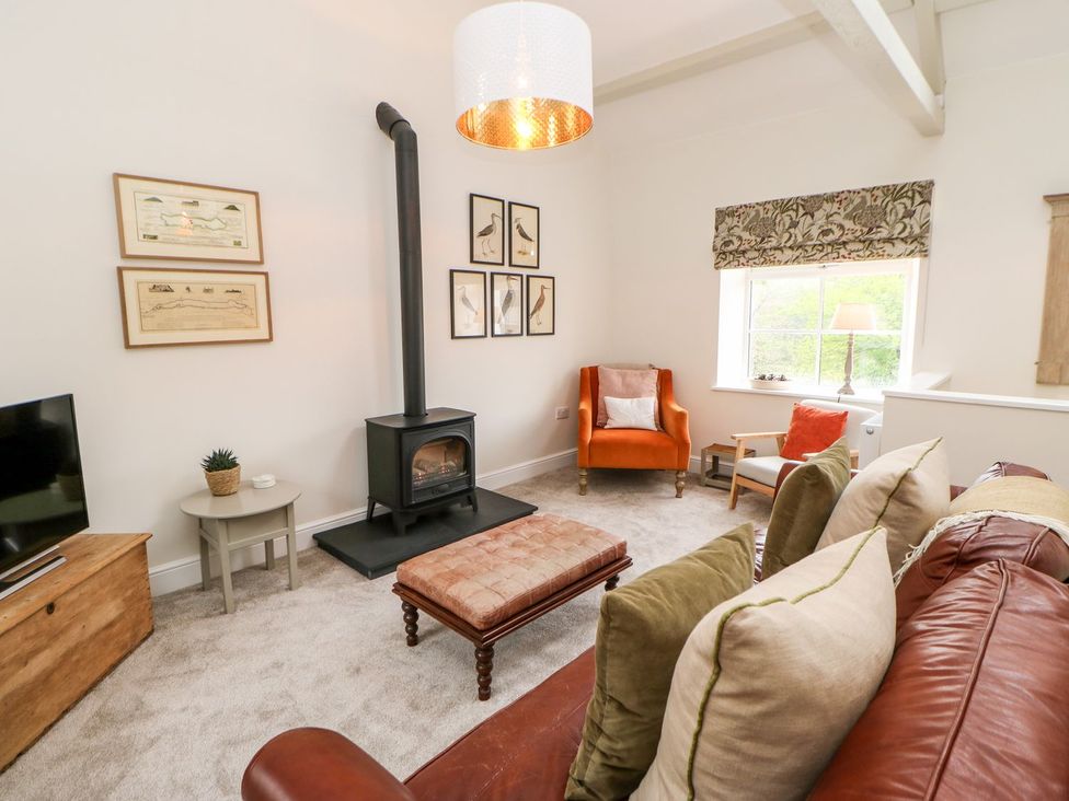 A living room with a stove and sofa at Dairy Cottage in Kirkby Stephen