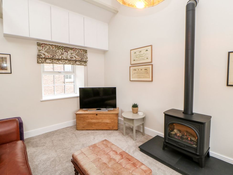A living room with a television and stove at Dairy Cottage in Kirkby Stephen