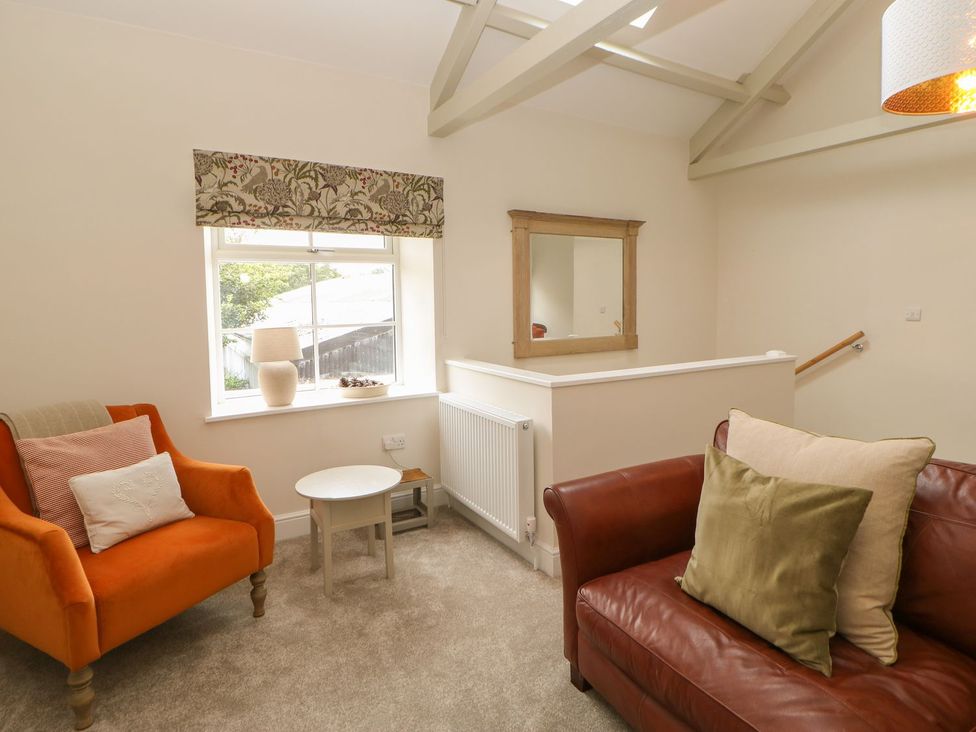 A living room with an orange armchair and brown sofa at Dairy Cottage in Kirkby Stephen