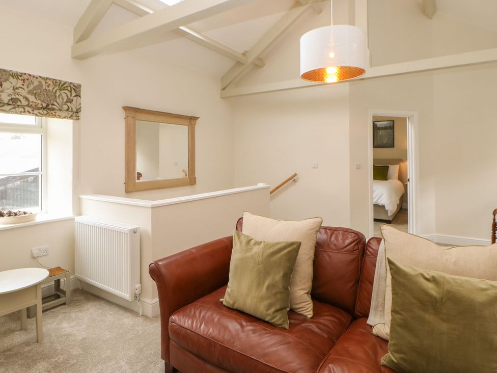 A living room with a sofa and mirror at Dairy Cottage in Kirkby Stephen
