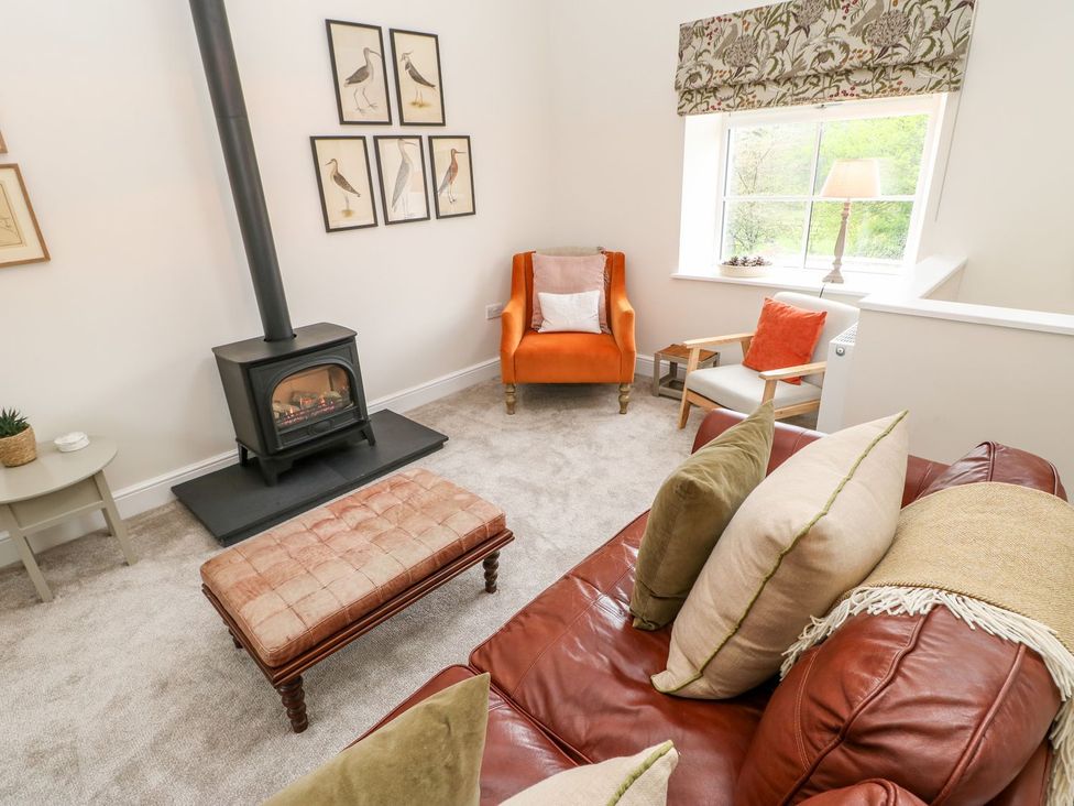 A living room with a wood stove and seating area at Dairy Cottage in Kirkby Stephen