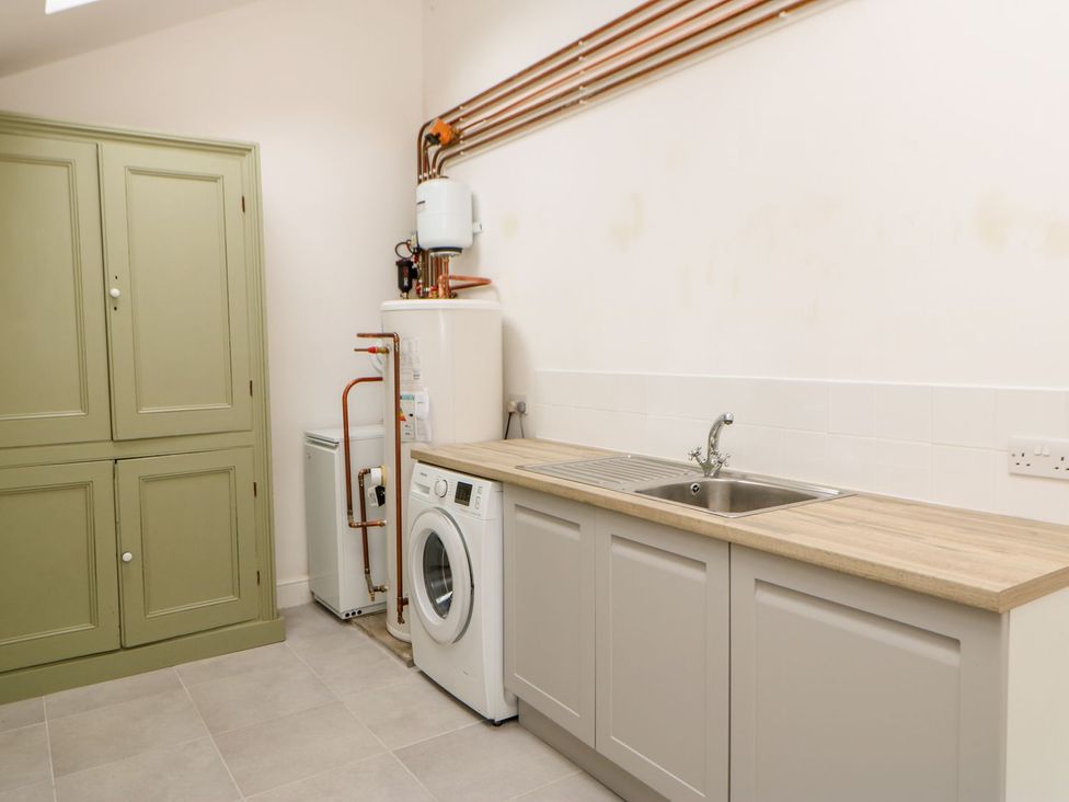 A laundry room with a washing machine and sink at Dairy Cottage in Kirkby Stephen