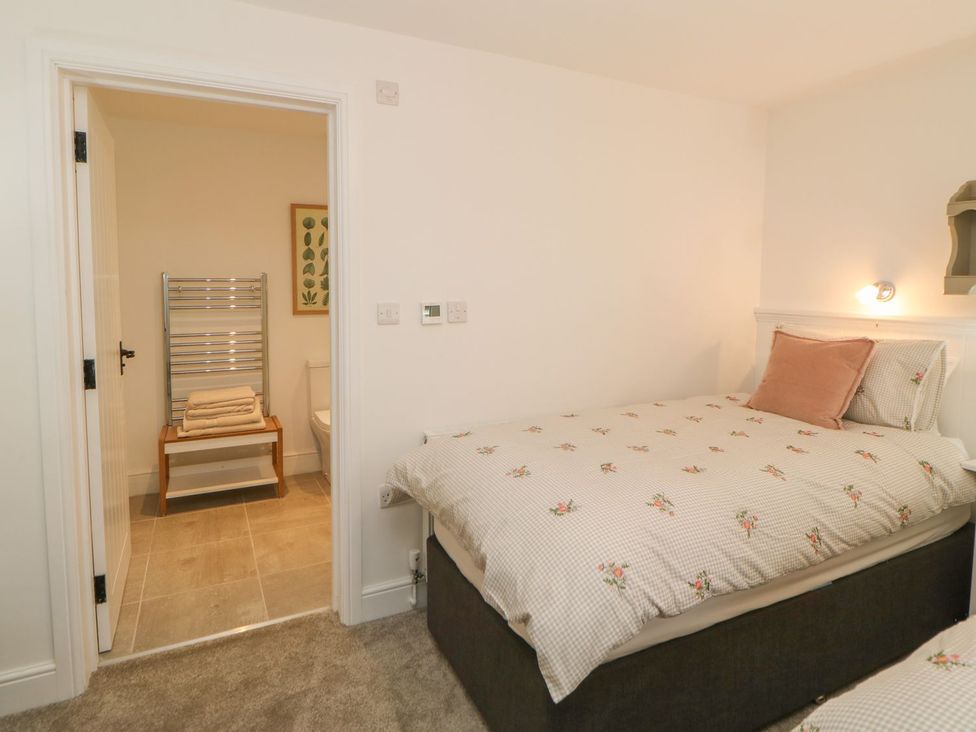 A bedroom with a bed and bathroom access at Dairy Cottage in Kirkby Stephen