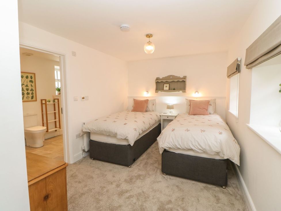 A bedroom with twin beds and a nightstand at Dairy Cottage in Kirkby Stephen