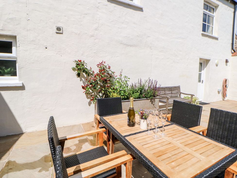 An outdoor patio with a wooden table and chairs at Dairy Cottage in Kirkby Stephen