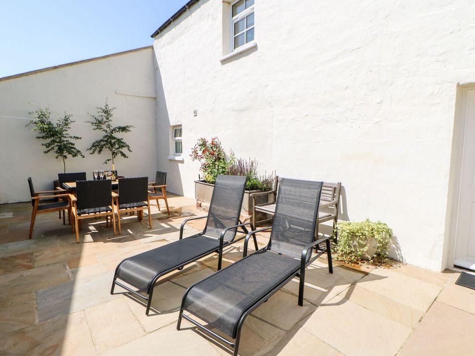 An outdoor area with sun loungers and a dining table at Dairy Cottage Kirkby Stephen