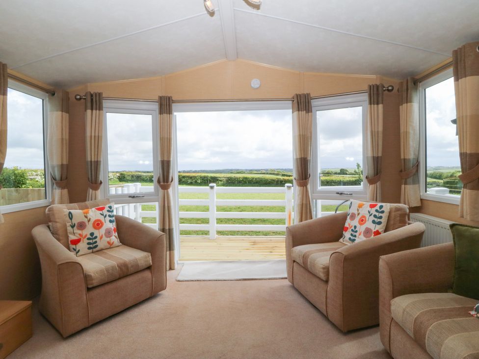 A snug area with seating and windows at Temperance Caravan Trefor near Bodedern