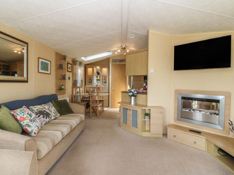 A living room with a sofa and dining area at Temperance Caravan in Trefor near Bodedern