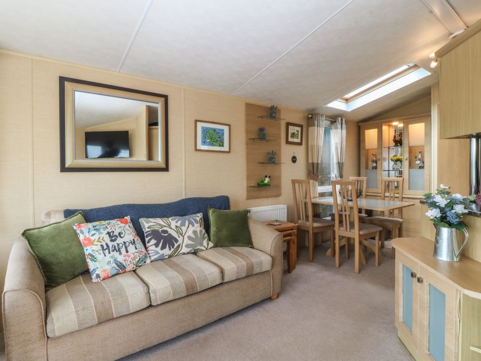 A living room with a sofa and dining area at Temperance Caravan Trefor near Bodedern