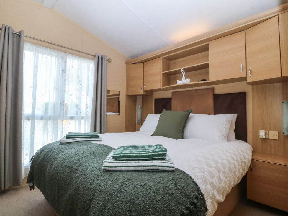 A bedroom with a bed and curtains at Temperance Caravan Trefor near Bodedern