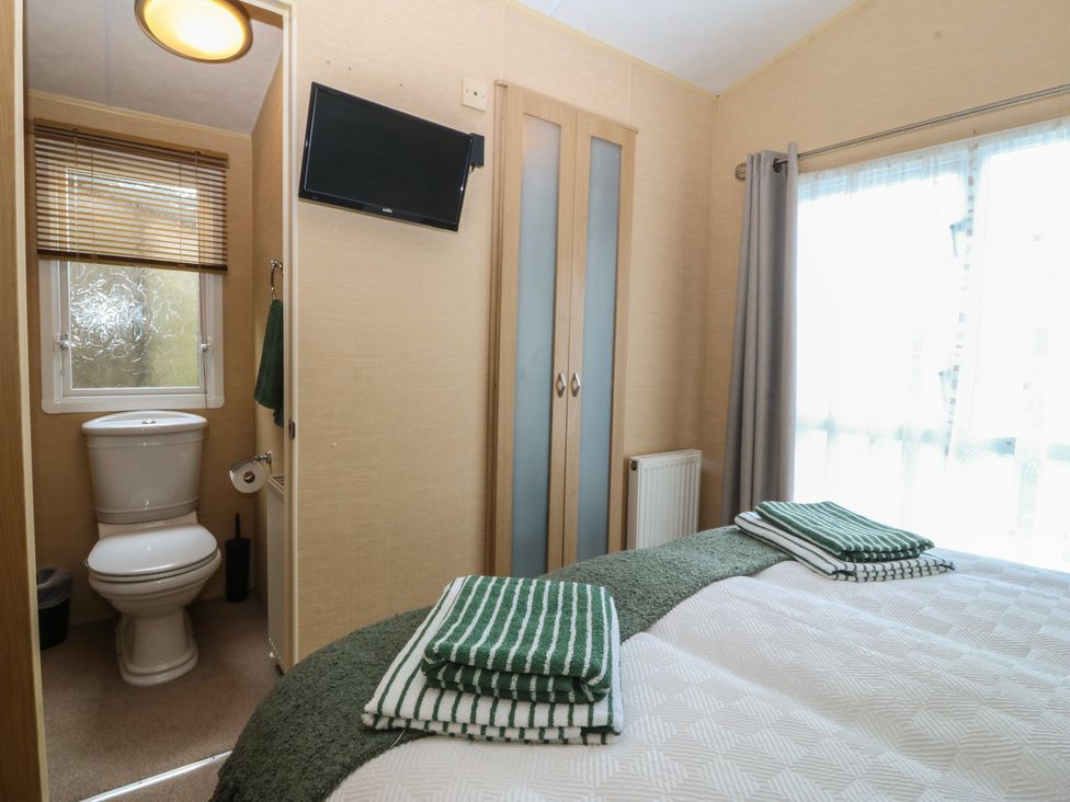 A bedroom with a bed and a bathroom visible at Temperance Caravan in Trefor near Bodedern