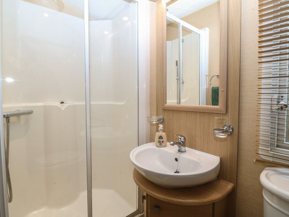 A bathroom with a shower and sink at Temperance Caravan, Trefor near Bodedern