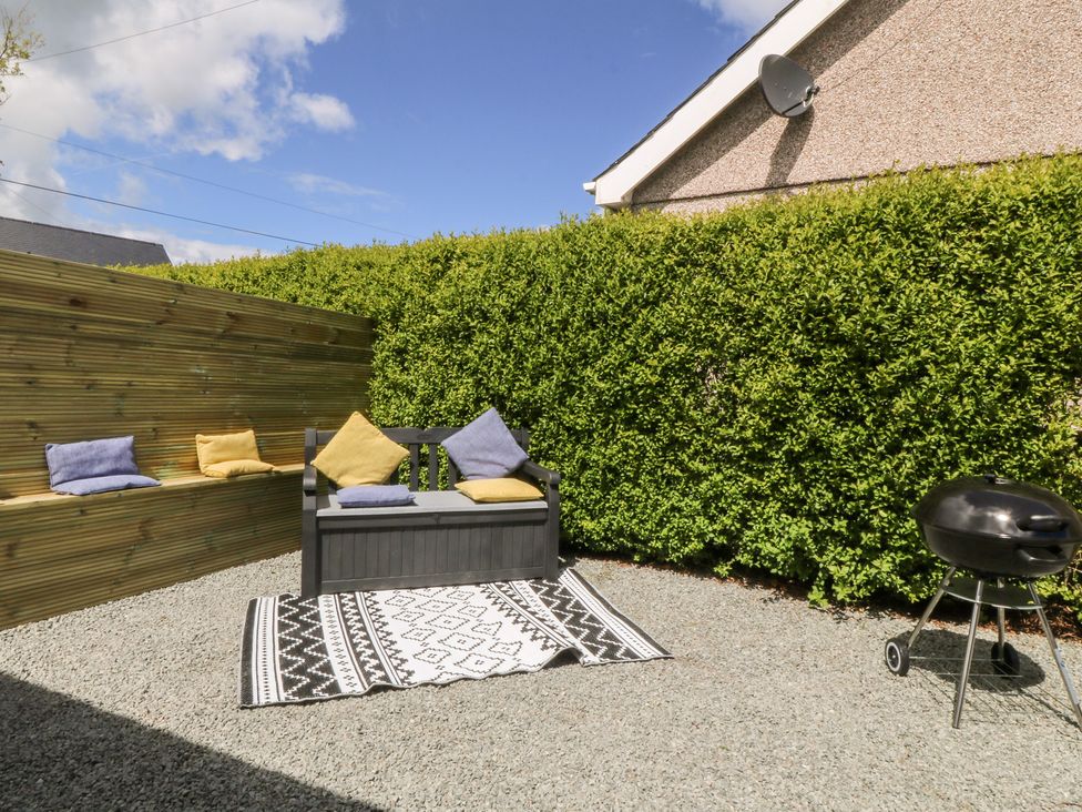 A garden with a bench and barbecue at Temperance Caravan in Trefor