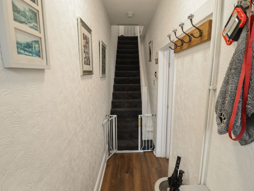 A hallway with a staircase and wall hooks at Pankhurst Cottage in Louth