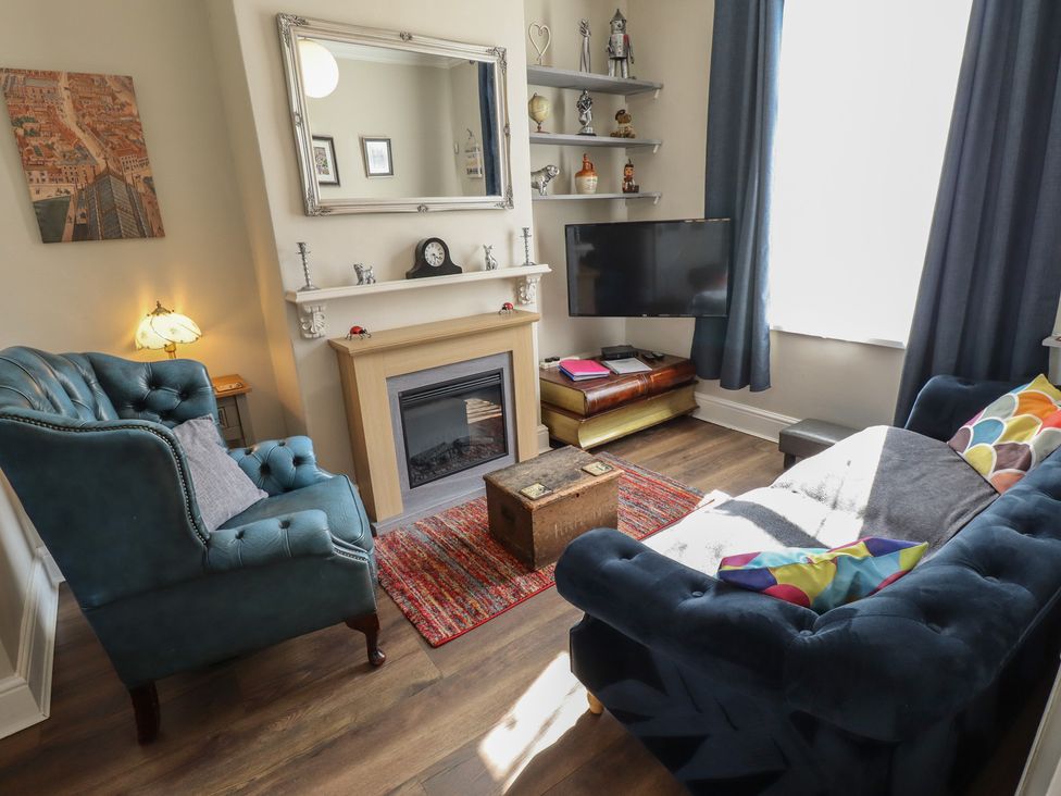 A living room with an armchair and a sofa at Pankhurst Cottage in Louth