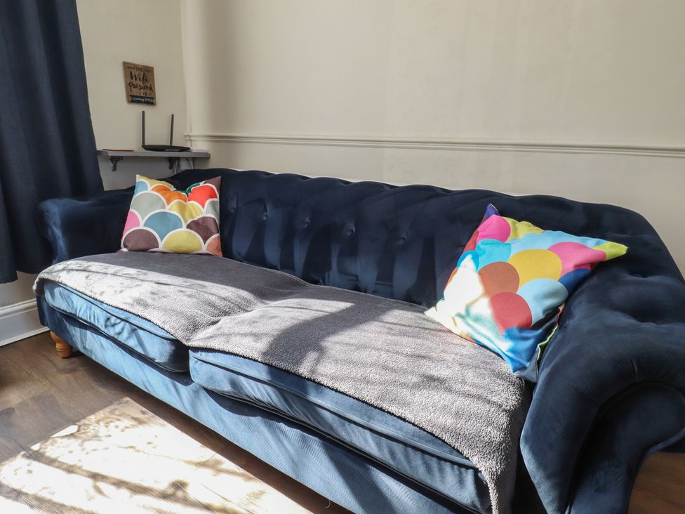 A sofa with cushions and a blanket at Pankhurst Cottage in Louth