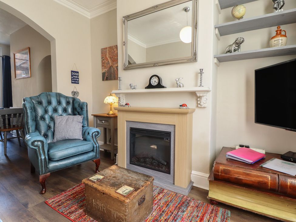 A living room with an armchair, fireplace, and television at Pankhurst Cottage in Louth