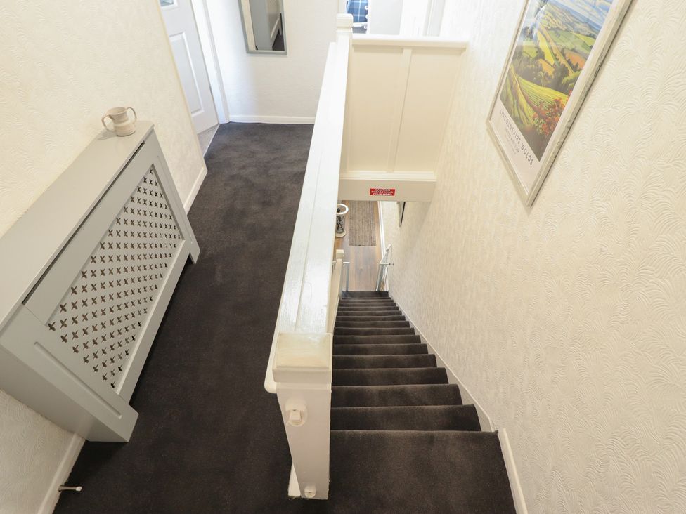 A staircase with a mirror and radiator in a hallway at Pankhurst Cottage in Louth