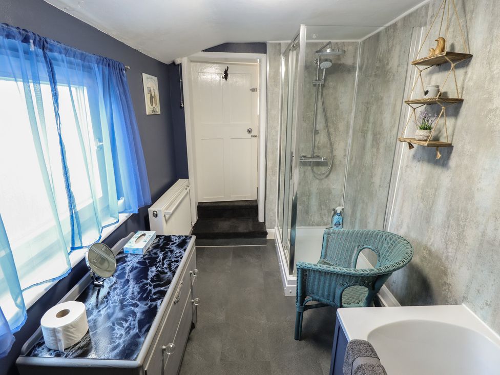 A bathroom featuring a shower, bathtub, and sink at Pankhurst Cottage in Louth