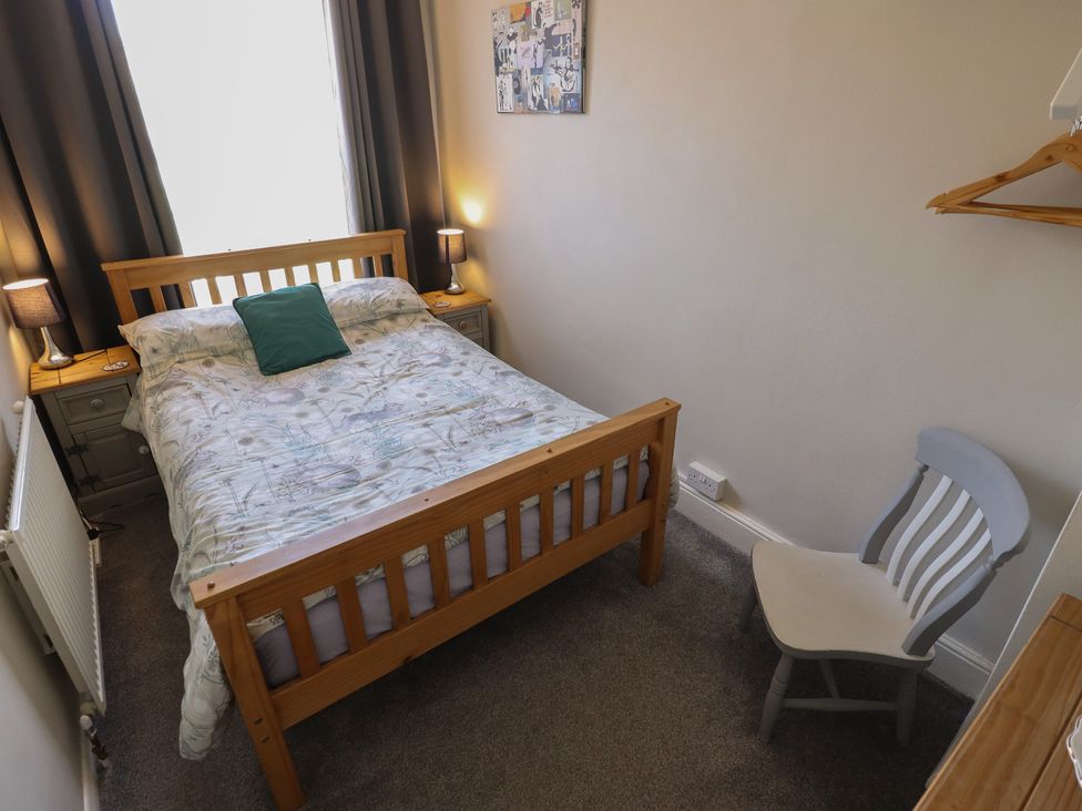 A bedroom with a bed, chair, and lamps at Pankhurst Cottage in Louth