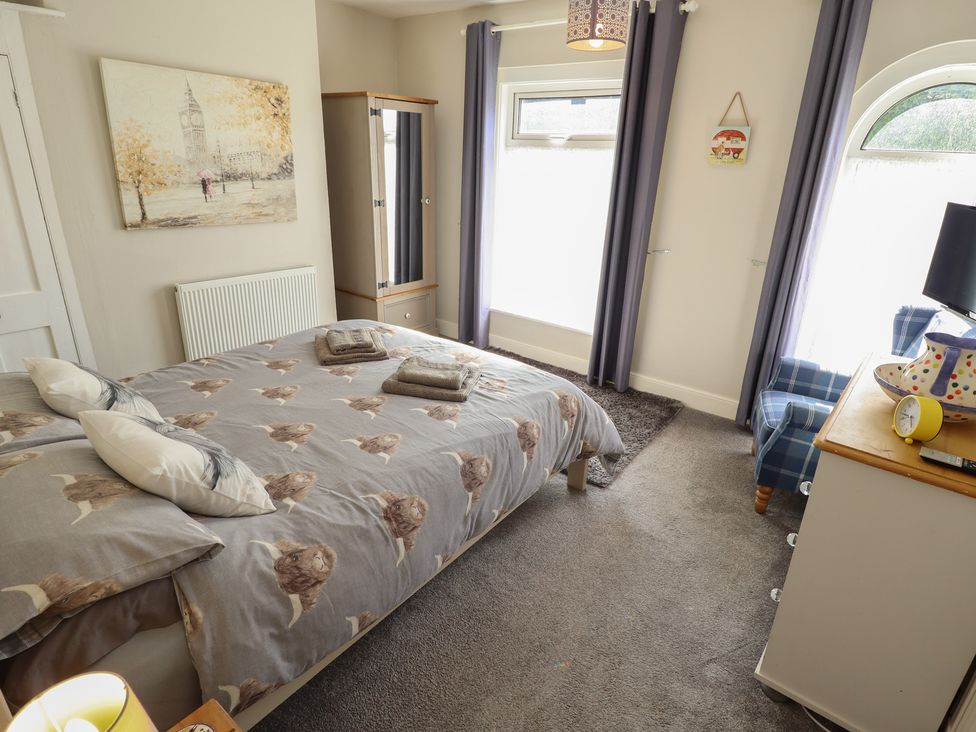 A bedroom with a bed and dresser at Pankhurst Cottage Louth