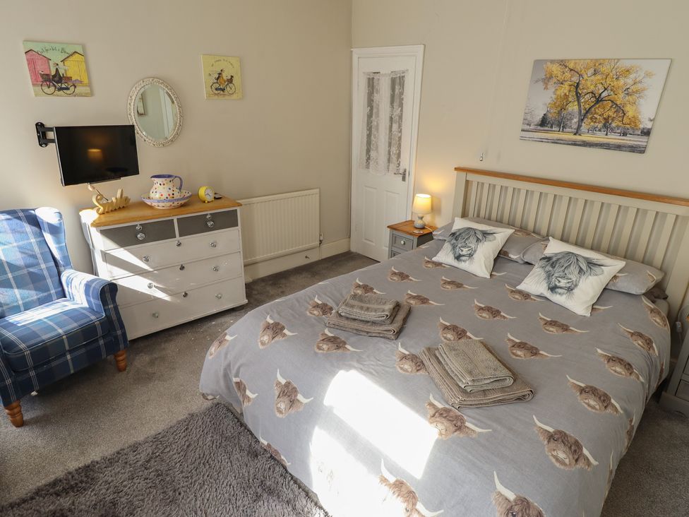 A bedroom with a bed and armchair at Pankhurst Cottage Louth