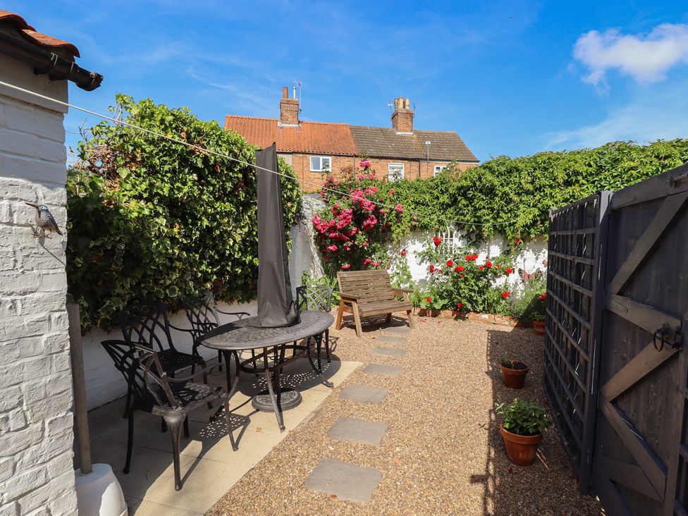 A garden with a stone pathway and table surrounded by chairs at Pankhurst Cottage in Louth