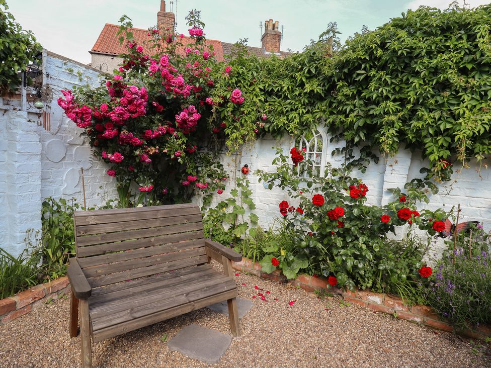 A garden with a wooden bench and flowers at Pankhurst Cottage in Louth