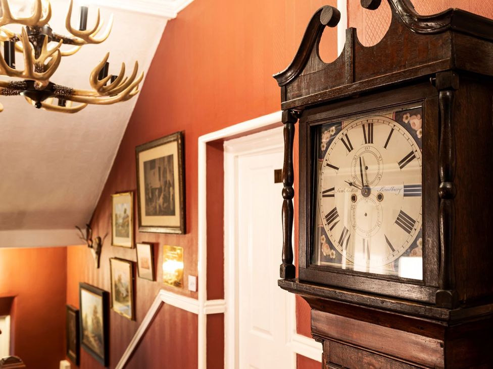 A hallway with a clock and paintings on the wall at Lonsdale House in Bowness-On-Windermere
