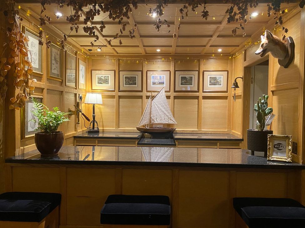 A lounge area with a bar counter and a sailing ship model at Lonsdale House Bowness-On-Windermere